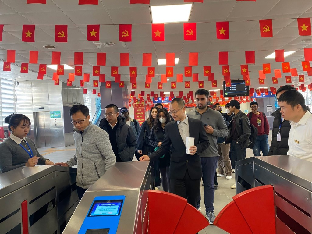 Người dân xếp hàng trật tự, trải nghiệm hệ thống soát vé điện tử tại nhà ga metro trong không gian được trang trí rực rỡ cờ hoa chào mừng Đại hội Đảng.