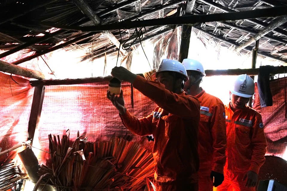 Công nhân Đội Quản lý điện lực khu vực Văn Yên lắp đặt, thay thế bóng đèn và thiết bị điện trong căn lều tạm của bà Bàn Thị Pham