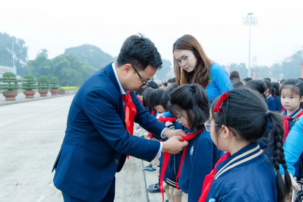 Thầy Nguyễn Văn Hà, Tổng phụ trách Đội Trường Tiểu học Đoàn Thị Điểm - Hà Nội trao khăn quàng đỏ đến các em học sinh