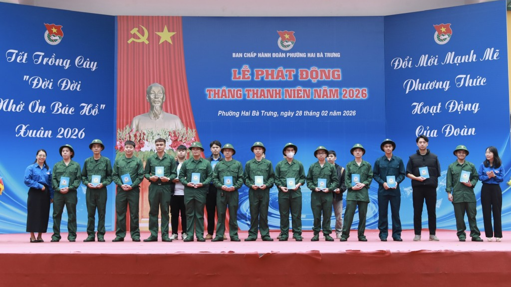 lên sân khấu để nhận Sổ Đoàn viên và Chứng nhận tân binh tự nguyện viết đơn nhập ngũ.