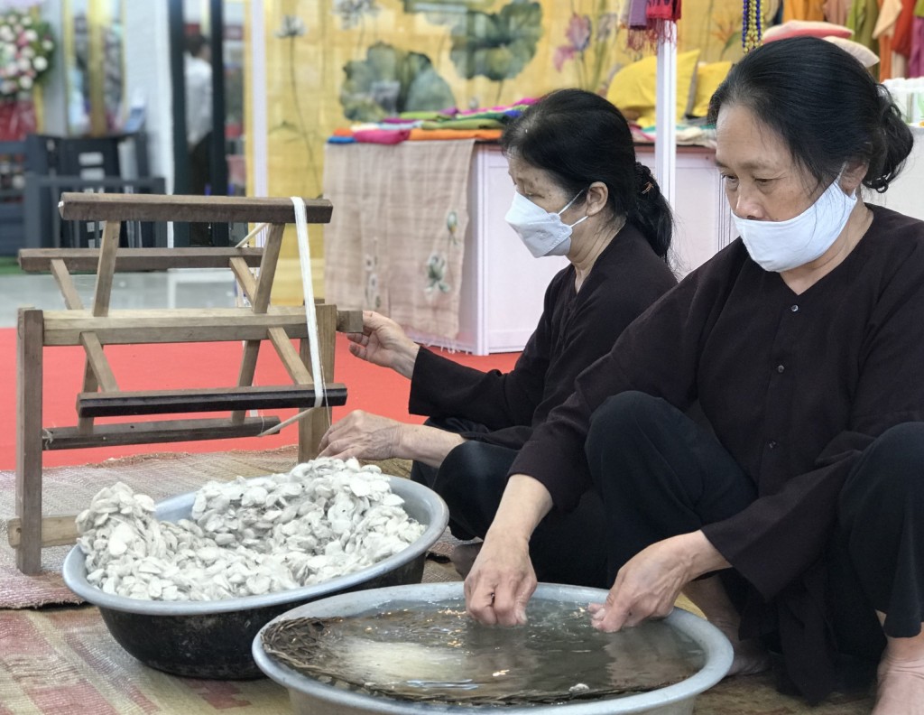 Một gian hàng tại triển lãm mô phỏng quá trình tuốt và quay tơ để tạo nên thước lụa tơ tằm (Ảnh Đ.Minh)