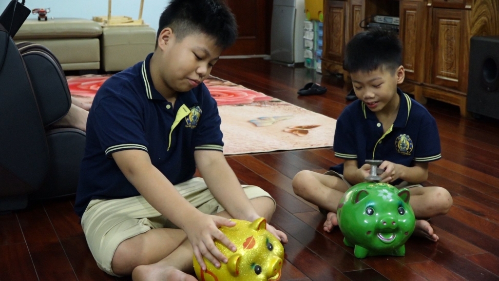 Hai em thiếu nhi Nguyễn Đức Anh lớp 6a4 trường THCS Xanh Tuệ Đức và em Nguyễn Huy Hiếu đập lợn đất để ủng hộ Quỹ Vaccine phòng chống dịch Covid-19