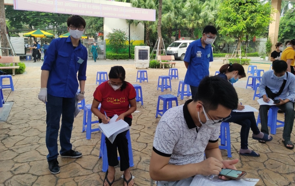 Lực lượng áo xanh tình nguyễn hướng dẫn người dân kê khai thông tin trước khi vào tiêm