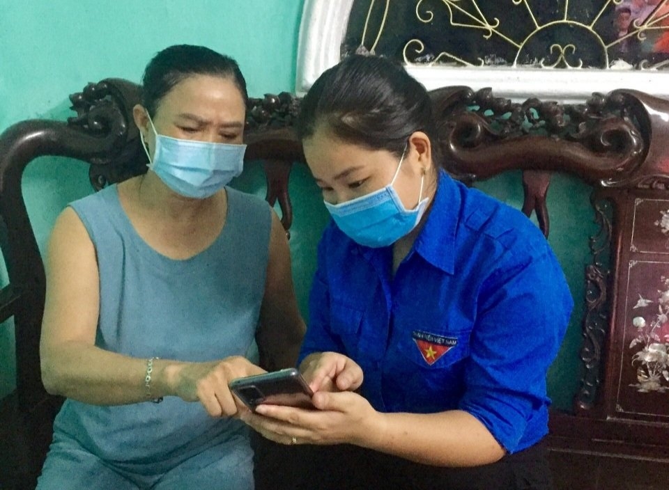 Chị Nguyễn Thị Hải Yến, Bí thư Đoàn xã Quảng Bị  giúp người dân cài app sức khoẻ điện tử tại nhà