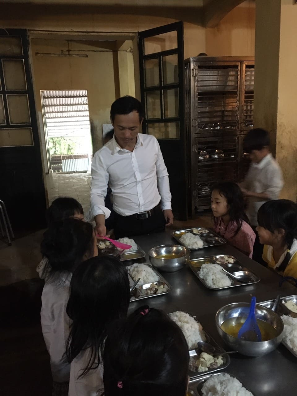 thầy giáo trẻ quan tâm đến bữa ăn bán trú của học sinh