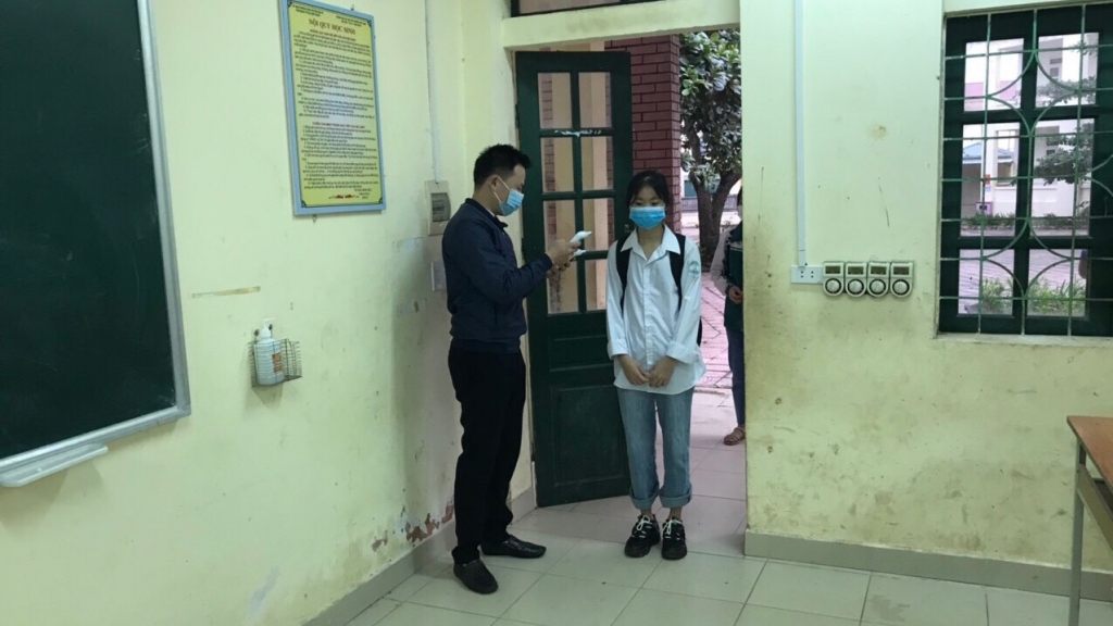 Giáo viên trường Phổ thông cơ sở Hợp Nhất đo thân nhiệt cho học sinh