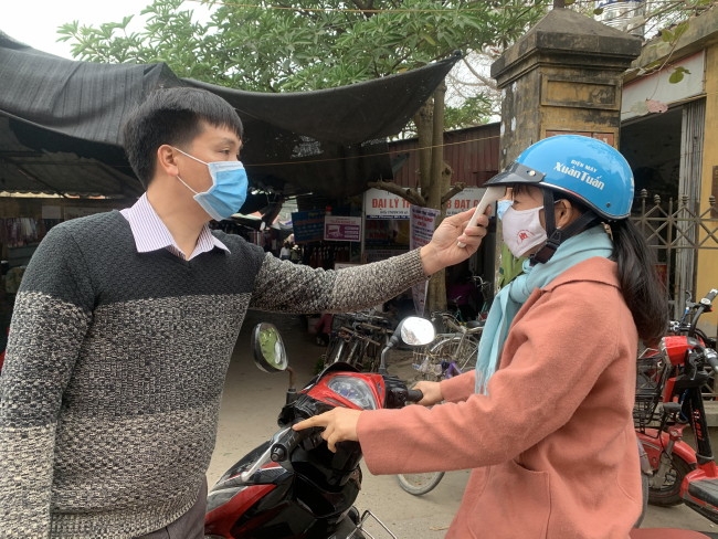 Đo thân nhiệt, nhắc nhở người dân đeo khẩu trang, sất khuẩn tay tại chợ Rưng (thị trấn Tứ Trưng)