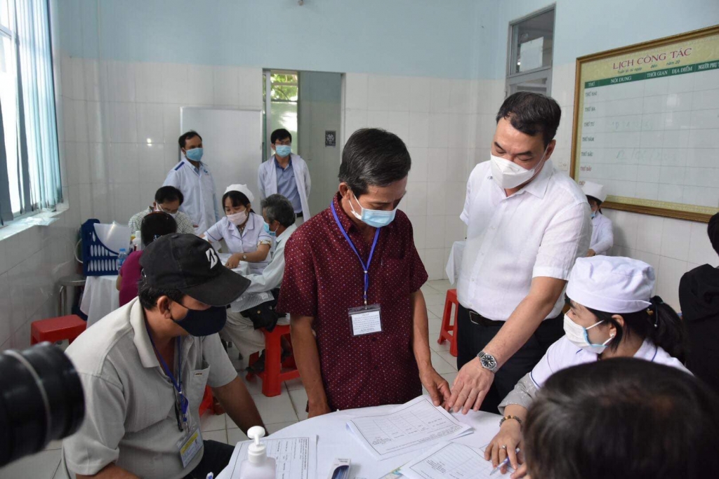 Tiến sĩ Nguyễn Ngô Quang, Phó Cục trưởng Cục Khoa học Công nghệ Đào tạo Bộ Y tế  (người đứng, áo trắng) kiểm tra thủ tục trước khi tiến hành tiêm thử nghiệm.