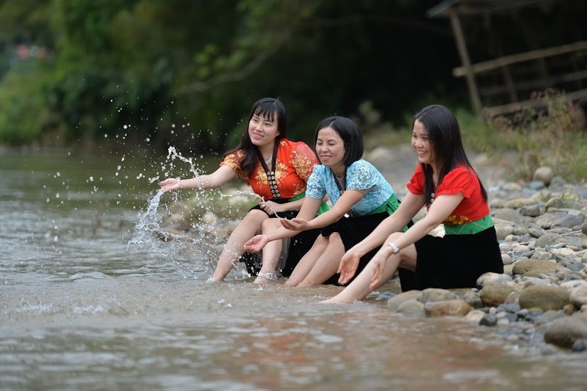 Du khách mặc trang phục dân tộc Thái chụp ảnh bên bờ suối bản Vàng Pheo