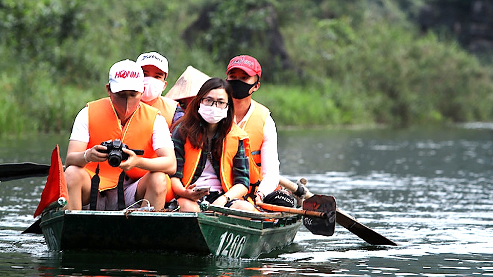 Du khách tuân thủ đeo khẩu trang, phòng chống dịch COVID-19 khi tham quan di tích Tràng An, tỉnh Ninh Bình.