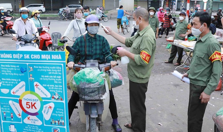 Kiểm tra thân nhiệt cho người dân tại chợ đầu mối Minh Khai (quận Bắc Từ Liêm). Ảnh: Vũ Sinh