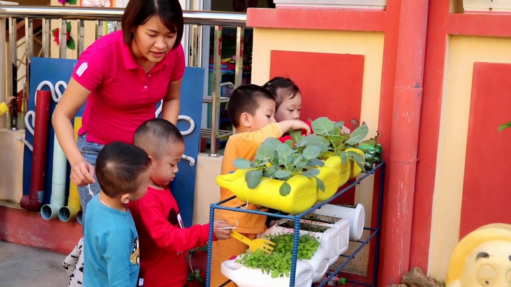 Cô giáo trường Mầm non Bông Sen hướng dẫn các bé chăm sóc cây được trồng trong những can nhựa (Ảnh: Quang Chương)