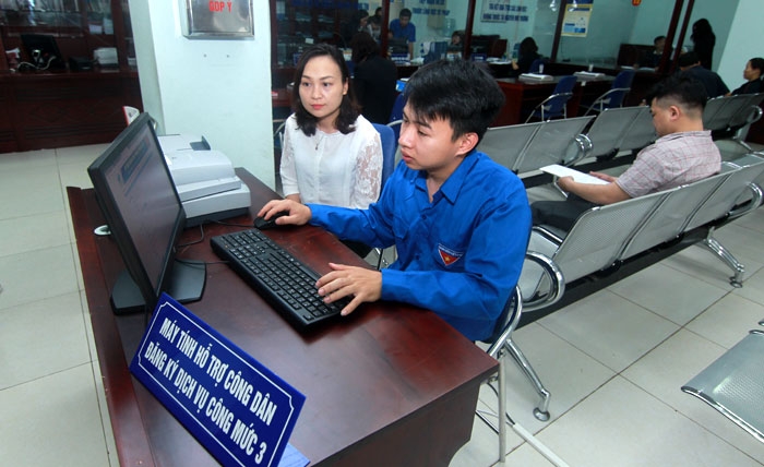 Hà Nội đẩy mạnh ứng dụng CNTT để xây dựng chính quyền điện tử (Trong ảnh: Cán bộ hướng dẫn người dân thực hiện thủ tục hành chính công tại UBND quận Bắc Từ Liêm)