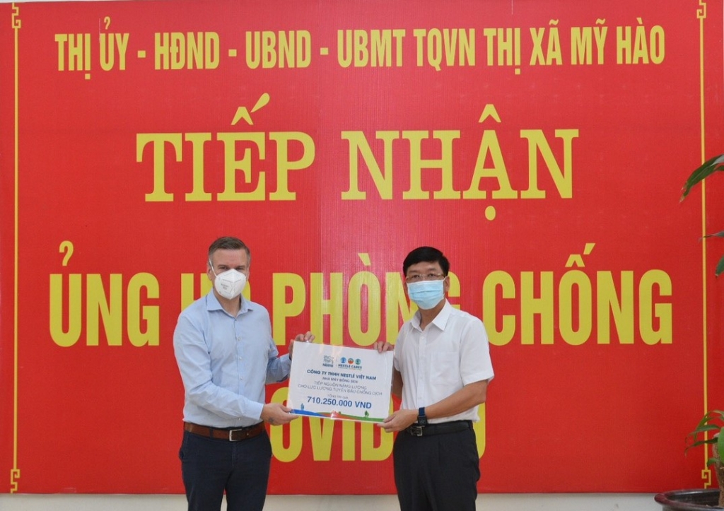 Ông Lê Quang Hiến, Chủ tịch UBND TX Mỹ Hào, tiếp nhận hỗ trợ từ Nestlé Việt Nam cho tuyến đầu chống dịch từ ông Urs Kloeti, Giám đốc Nhà máy Nestlé Bông Sen