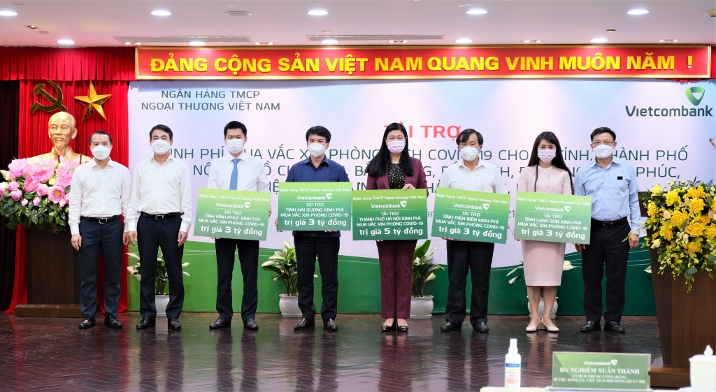 Đại diện Ban lãnh đạo Vietcombank, trao kinh phí tài trợ mua vắc xin phòng Covid-19 cho các tỉnh thành phố gồm: Hà Nội, Vĩnh Phúc, Hải Dương, Điện Biên, Lạng Sơn tại điểm cầu Trụ sở chính Vietcombank tại Hà Nội