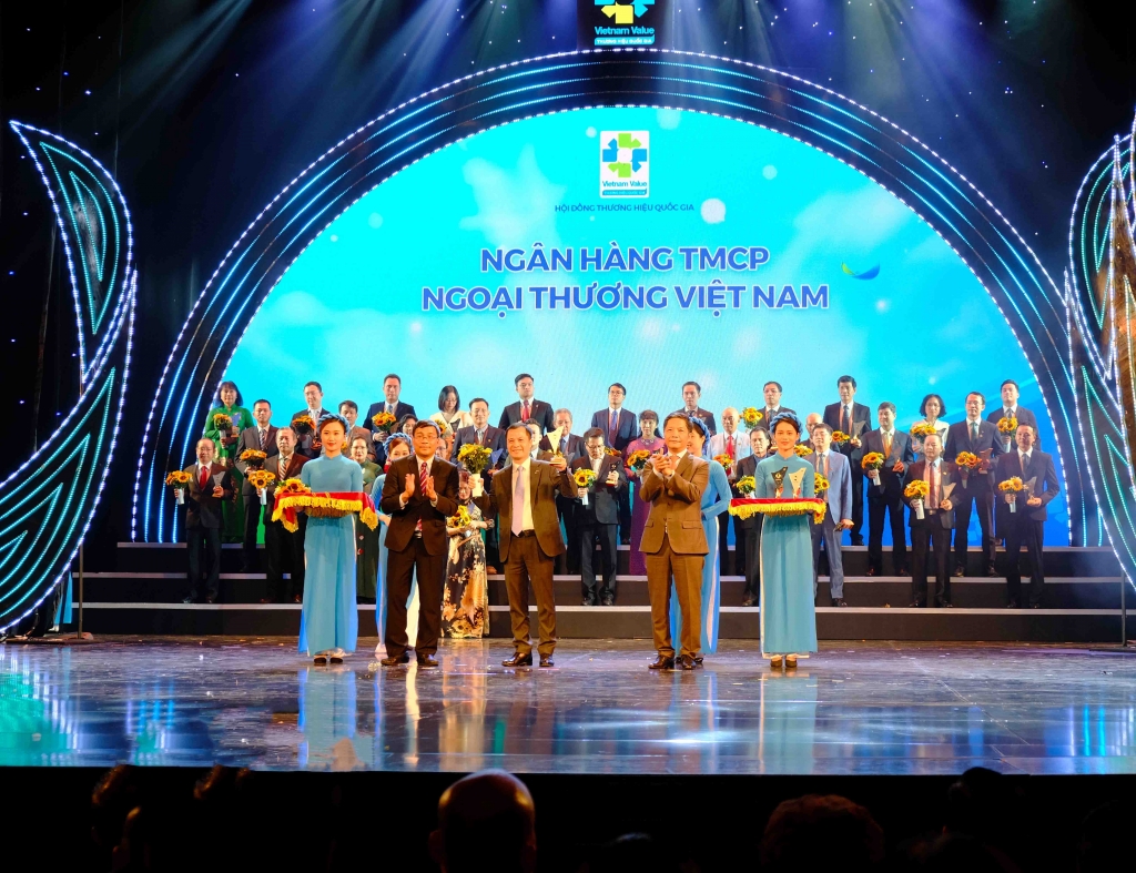 Đại diện Vietcombank, ông Lê Hoàng Tùng – Kế toán trưởng nhận biểu trưng Thương hiệu quốc gia cùng hoa chúc mừng từ Bộ trưởng Bộ Công thương Trần Tuấn Anh và đại diện Hội đồng Thương hiệu Quốc gia
