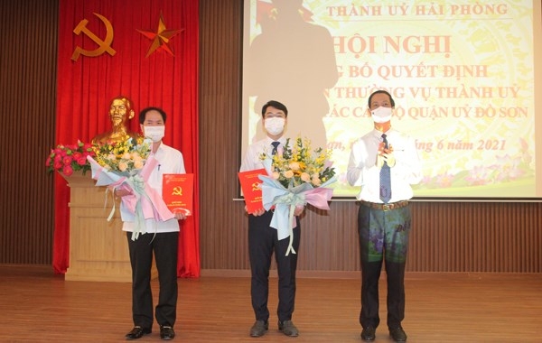 Đồng chí Đỗ Mạnh Hiến, Phó Bí thư Thường trực Thành ủy trao Quyết định và tặng hoa cho đồng chí Hoàng Xuân Minh và đồng chí Nguyễn Quang Diện