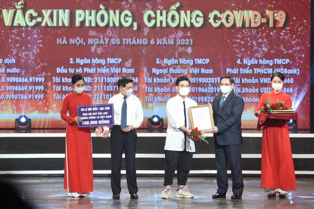 Thủ tướng Chính phủ Phạm Minh Chính trao chứng nhận, hoa cảm ơn em Lê Đức Hiếu, học sinh Trường Phạm Hồng Thái, Ba Đình, Hà Nội, 15 tuổi. Ảnh VGP