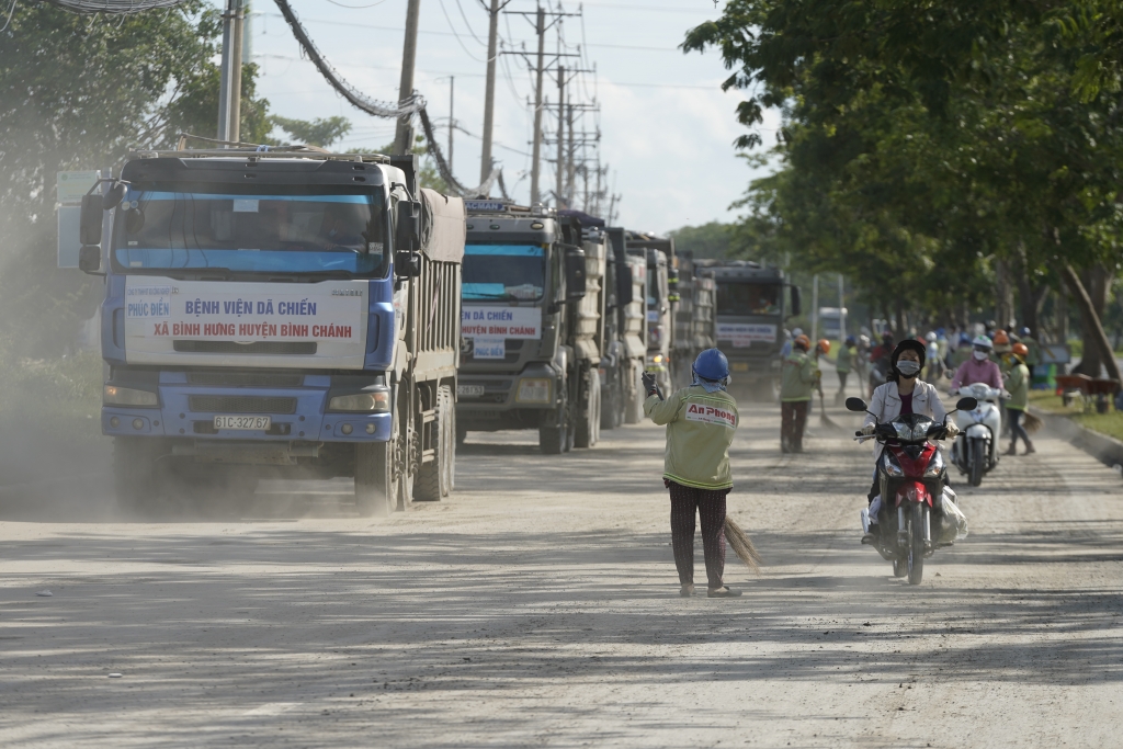 hàng chục lượt xe tải trọng lớn chở đất đá, cát xếp hàng dài trên đại lộ Nguyễn Văn Linh (xã Bình Hưng, huyện Bình Chánh, TP HCM) nối đuôi vào, ra công trường thi công bệnh viện dã chiến có quy mô 5,6ha