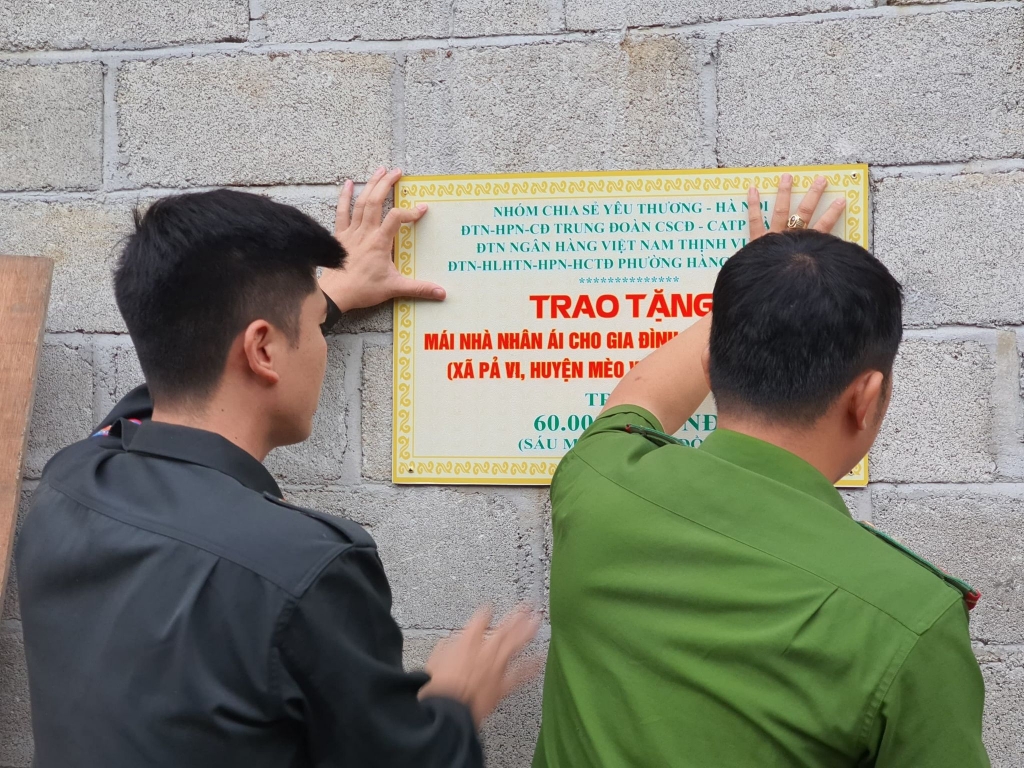 Đoàn viên thanh niên Trung đoàn Cảnh sát Cơ động (Công an thành phố Hà Nội) gắn biển tặng nhà cho gia đình chị 