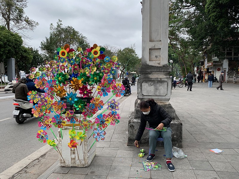 Người phụ nữ tranh thủ lắp thêm những món đồ chơi phục vụ các cháu thiếu nhi trong ngày đầu xuân 