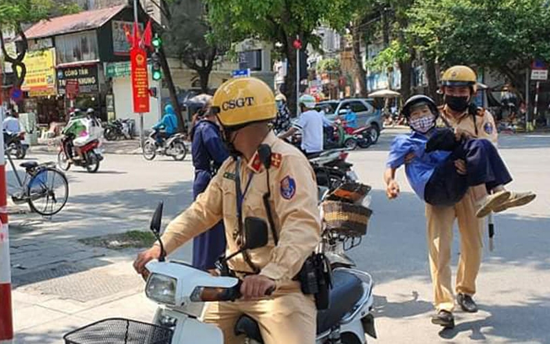 Chiến sỹ Cảnh sát giao thông Công an TP Hà Nội nhanh chóng bế cụ bà đưa đi cấp cứu