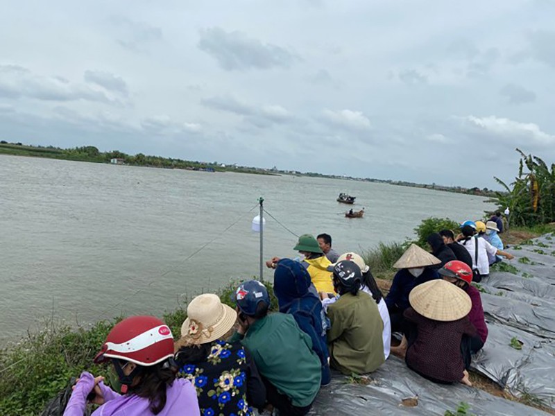 Người thân ngồi trên bờ sông trông ngóng lực lượng chức năng xã Cẩm Văn (huyện Cẩm Giàng, tỉnh Hải Dương) tìm kiếm nạn nhân mất tích