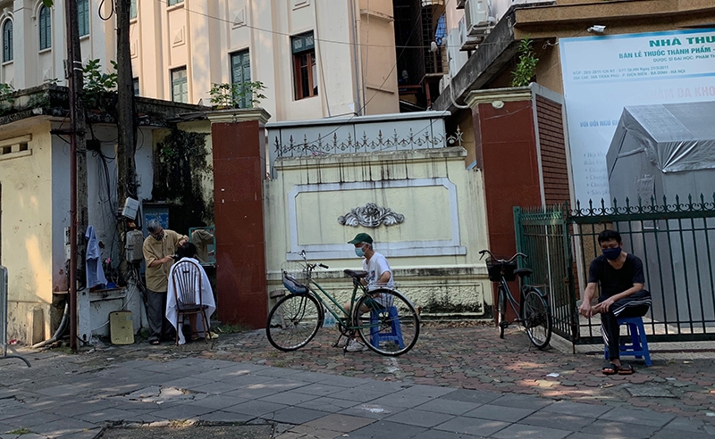 Khách đến cửa hàng cắt tóc trên phố Điện Biên giữ khoảng cách phòng dịch