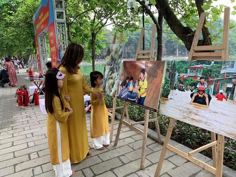 Một phụ nữ cho các bé tới phố đi bộ chơi đã tranh thủ giới thiệu cho các con về những bức ảnh PCCC và CNCH