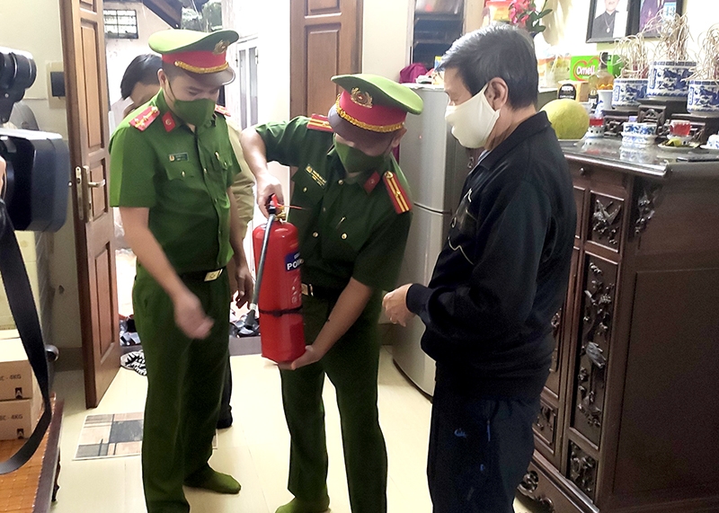 Thiếu tá Nguyễn Duy Quý, Phó Trưởng Công an phường Cửa Nam hướng dẫn hộ dân sử dụng bình chữa cháy