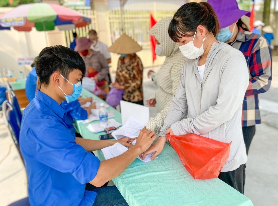 Tình nguyện viên hỗ trợ người dân nhập thông tin tiêm chủng tại điểm tiêm chủng trên địa bàn TX Đông Triều.