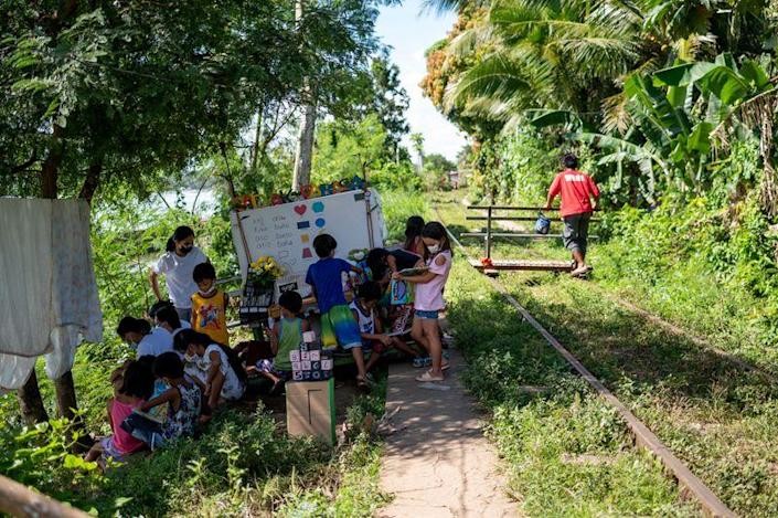  Những đứa trẻ thu mình trên bãi cỏ cạnh đường ray, xem những cuốn sách tiếng Anh (Ảnh: Reuters)