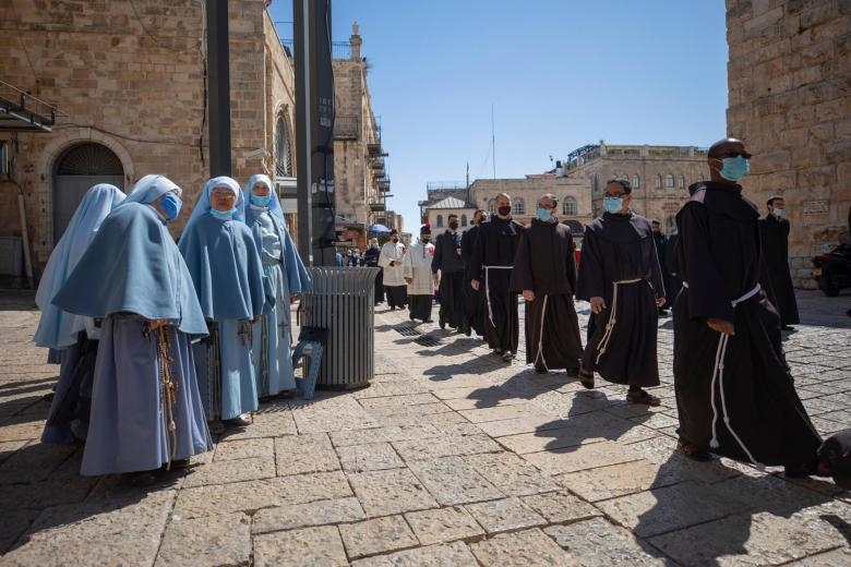 Các linh mục đeo khẩu trang diễu hành sau thánh lễ tại Thành cổ Jerusalem (Ảnh AP)