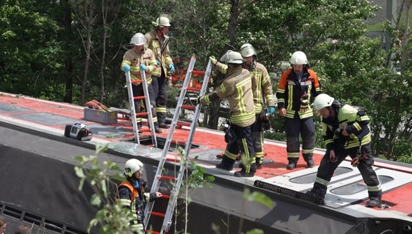  Các nhân viên cứu hộ đưa hành khách thoát ra từ cửa sổ của toa tàu bị lật tại Đức (Ảnh: AFP)