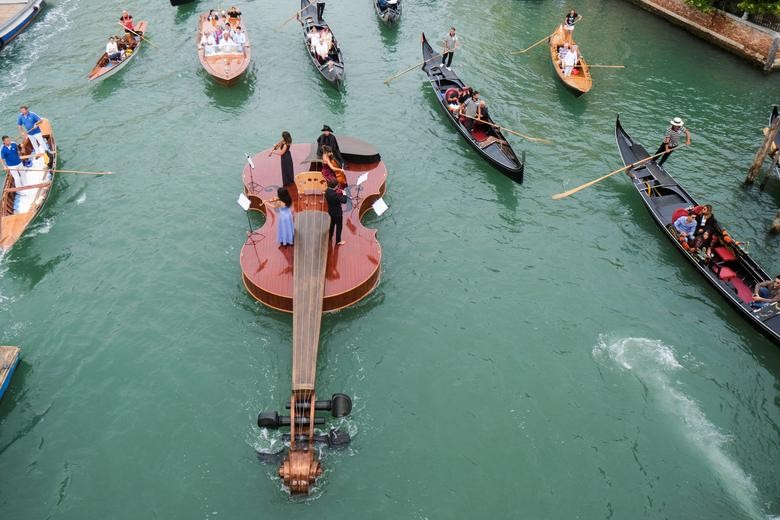 Các nhạc công biểu diễn trên chiếc thuyền có hình cây đàn violin tại Venice, Italy ngày 18/9. Chiếc thuyền với hình dáng 1 cây vĩ cầm khổng lồ đã được nghệ sĩ Livio De Marchi tạo ra để tưởng nhớ những người thiệt mạng vì Covid-19
