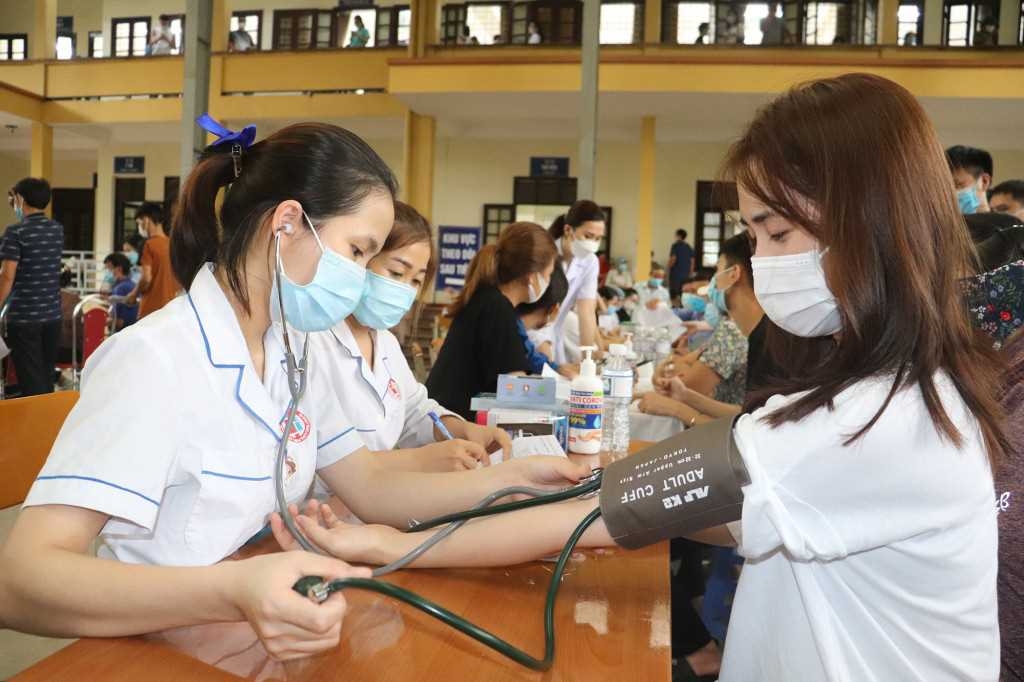 Người dân đo huyết áp, kiểm tra sức khỏe trước khi tiêm phòng.