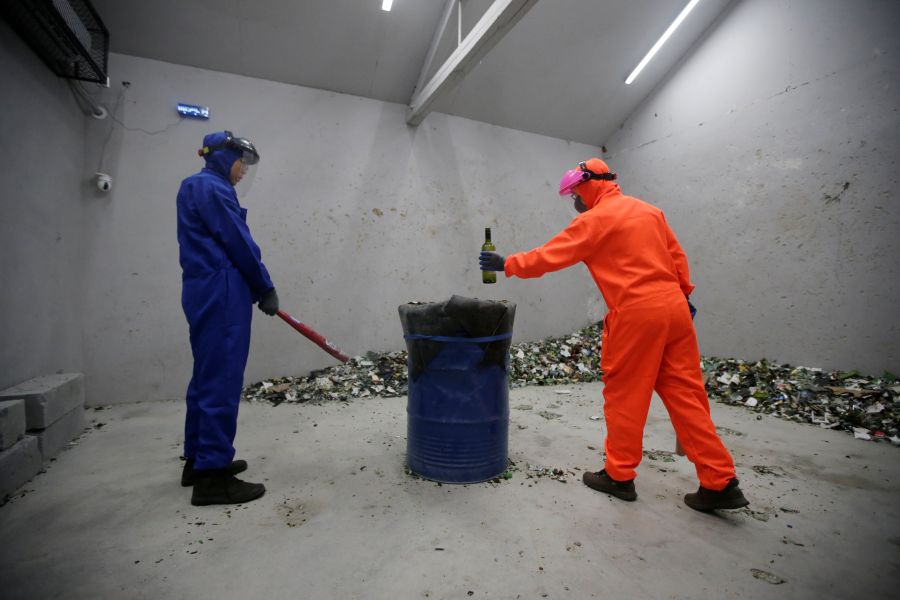 Người mặc đồ cam là bà mẹ cùng con trai cùng trải nghiệm dịch vụ này để xả stress. Bà đang đặt chai cho con trút giận. Ảnh: Reuters