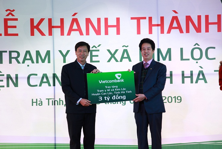 Ông Nguyễn Mỹ Hào – Ủy viên Hội đồng quản trị Vietcombank (bên phải) trao biển tượng trưng số tiền 3 tỷ đồng tài trợ của Vietcombank để xây dựng Trạm Y tế xã Kim Lộc cho đại diện lãnh đạo địa phương