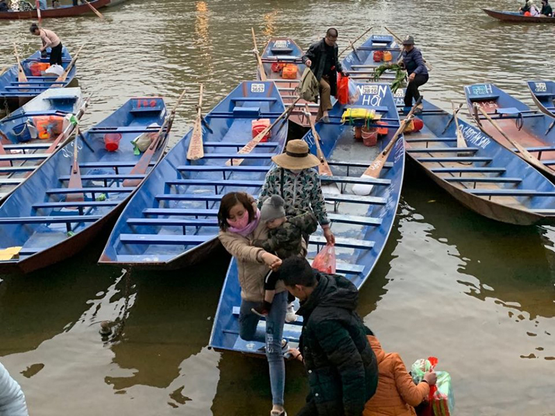 Một phụ nữ bế con nhỏ bước xuống đò trong khi không có phao cứu sinh