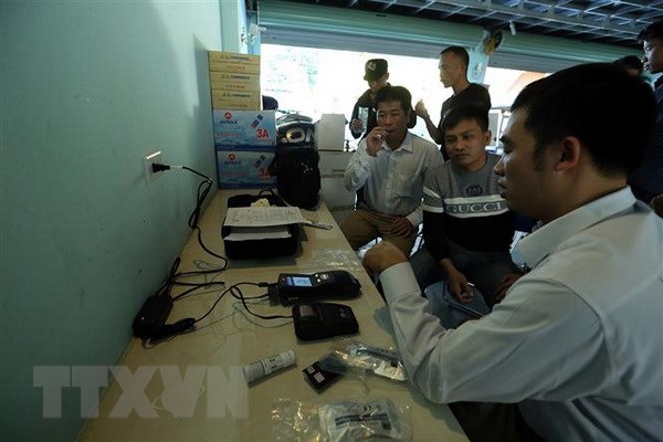 Các lực lượng chức năng tiến hành kiểm tra chất ma túy đối với lái xe. (Ảnh: Phan Tuấn Anh/TTXVN)