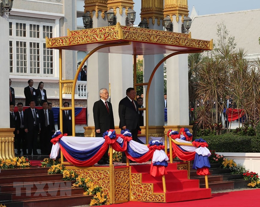 Tổng Bí thư, Chủ tịch nước Lào Bounnhang Vorachith và Tổng Bí thư, Chủ tịch nước Nguyễn Phú Trọng trên bục danh dự, thực hiện nghi thức chào cờ tại lễ đón. (Ảnh: Trí Dũng/TTXVN)