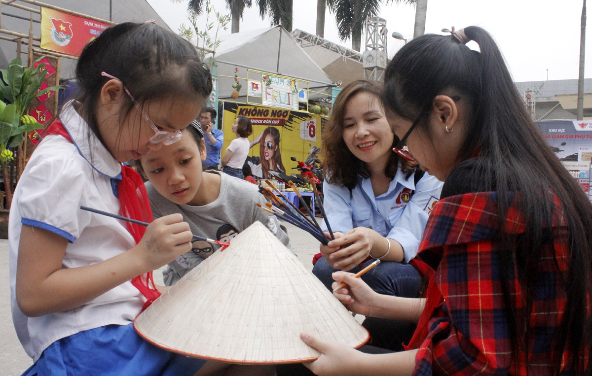 Các em thiếu nhi vẽ tranh tại liên hoan họa sỹ nhí bằng việc vẽ trên nhiều chất liệu khác nhau như nón, giấy, đá...