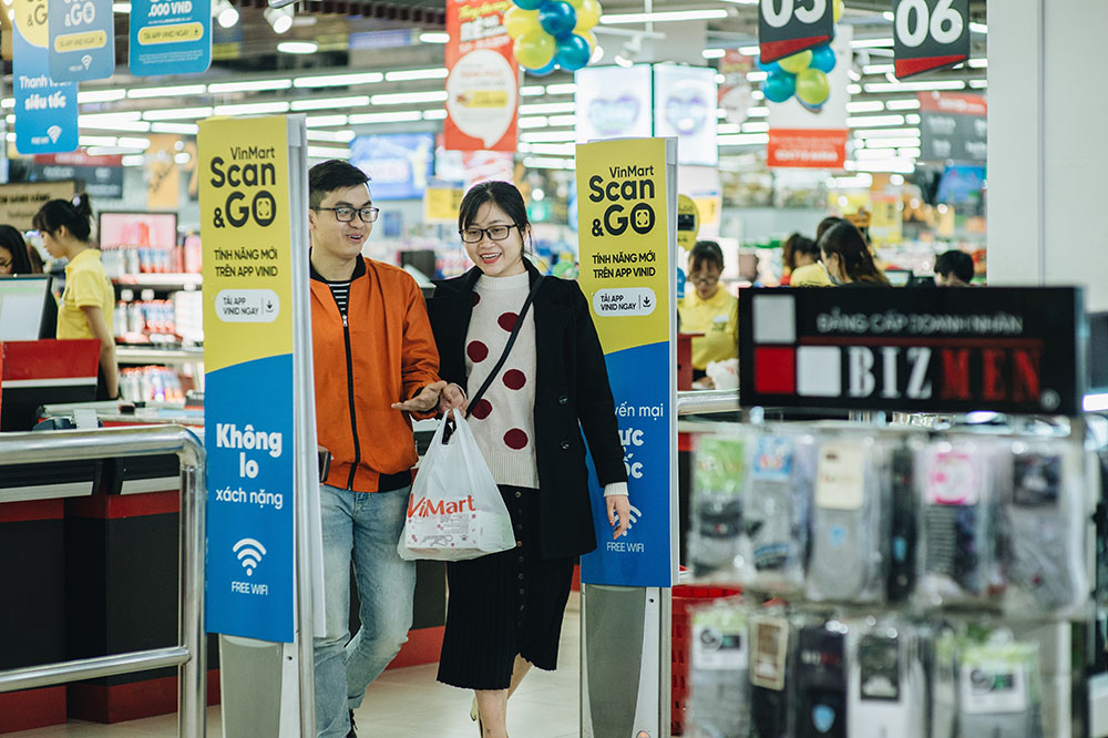 Một đôi vợ chồng trẻ vui vẻ xách đồ ra về sau khi “thanh toán siêu tốc” bằng VinMart Scan &amp;Go.