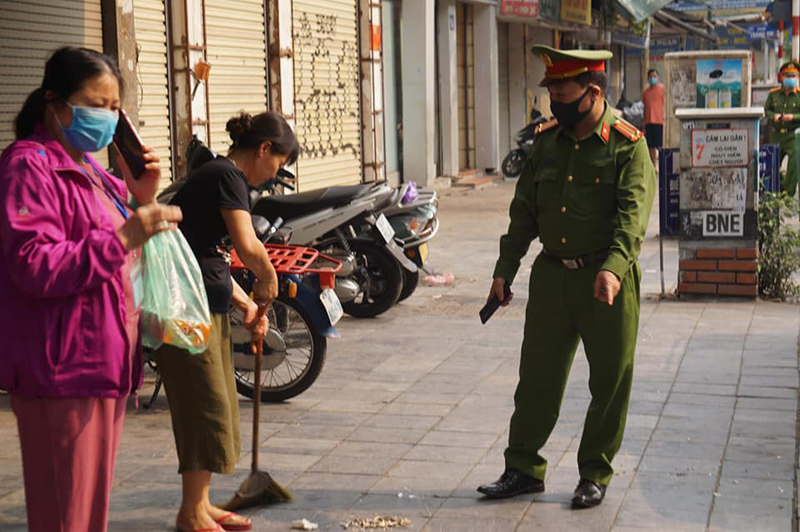 Công an quận Hoàn Kiếm, Hà Nội đi vận động các hộ kinh doanh đóng cửa hàng, dọn vệ sinh nhằm ngăn chặn dịch Covid-19