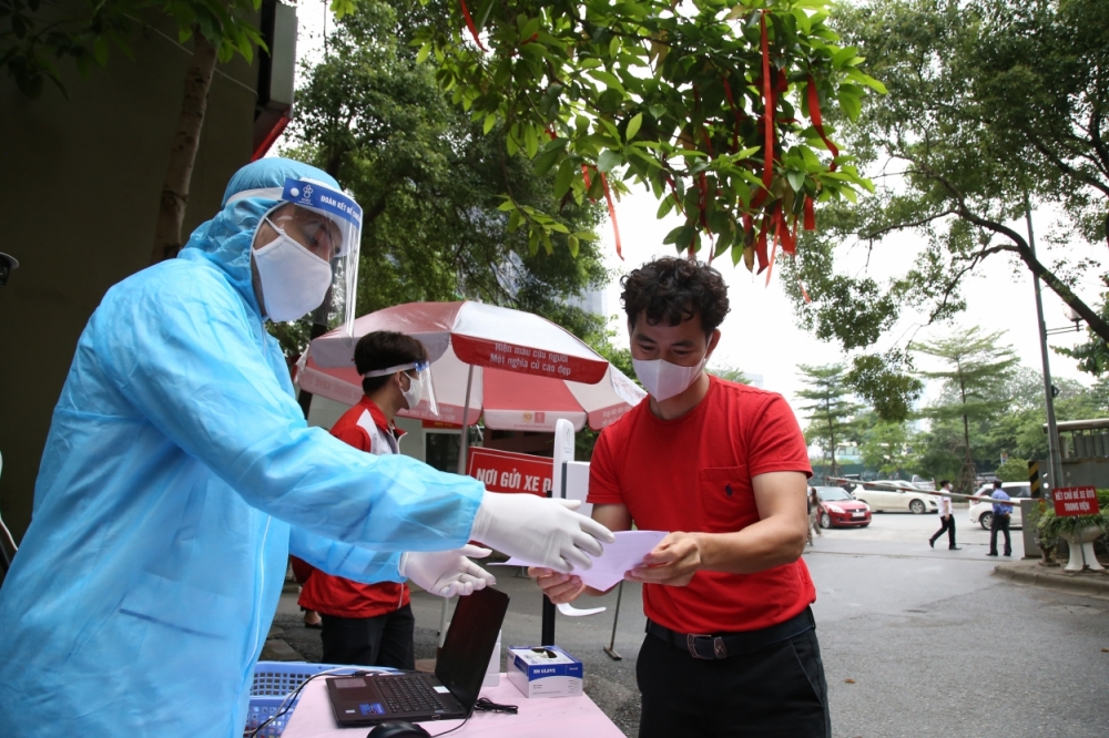 NSƯT Xuân Bắc nhận tờ khai đăng kí tham gia hiến máu sau khi đo thân nhiệt, sát khuẩn tay