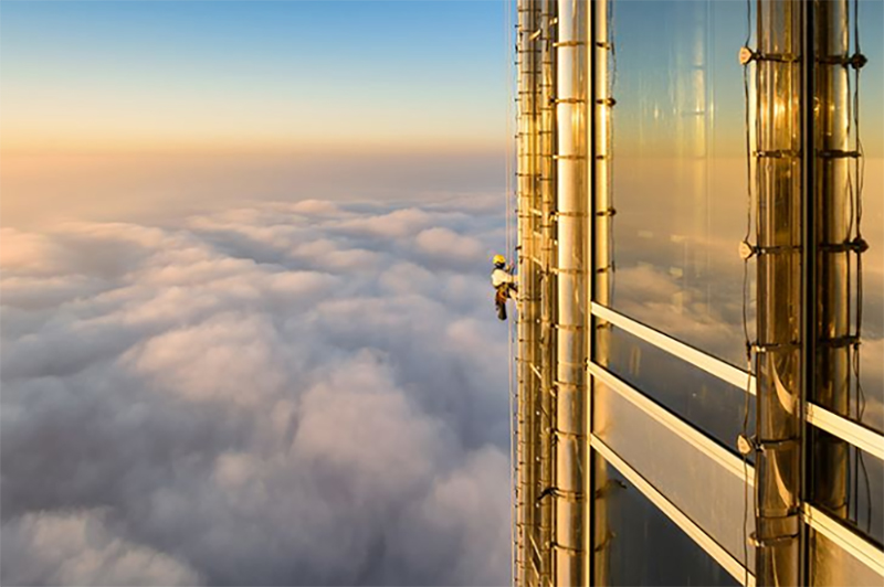 Một người treo mình lau cửa kính dọc theo mặt trước của Burj Khalifa ở Dubai, Tiểu vương quốc Ả Rập Thống nhất.