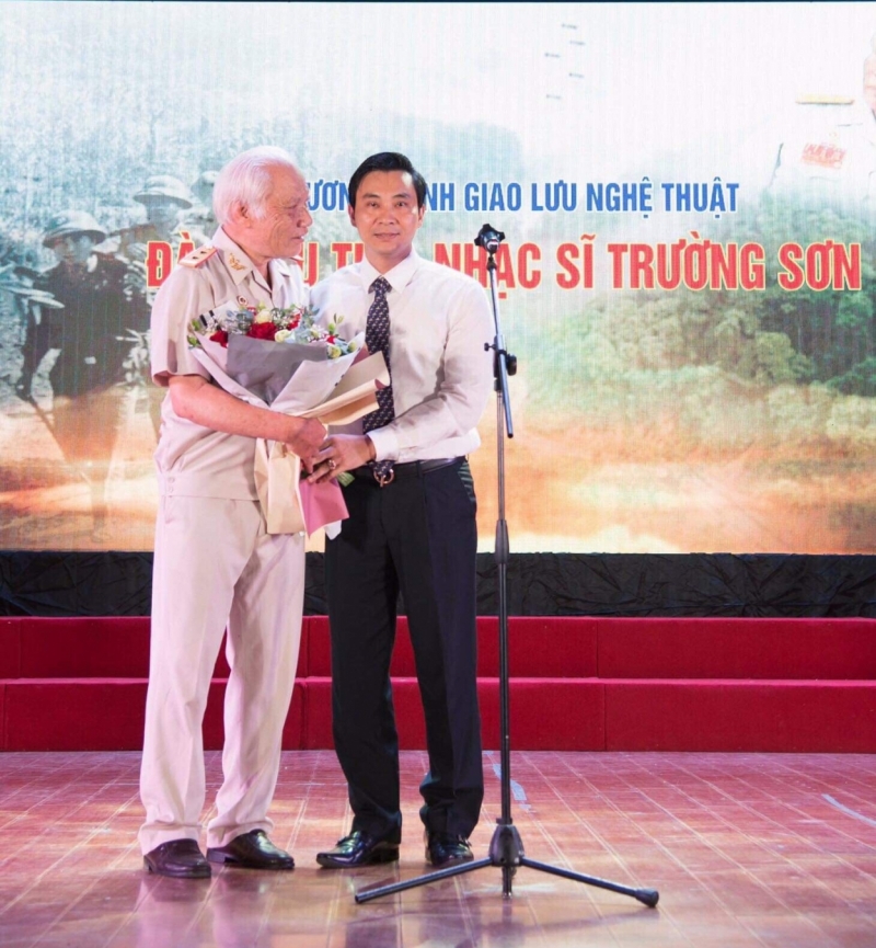 Tiến sĩ Đinh Công Tuấn - phó hiệu trưởng trường Đại học Văn Hoá tặng hoa chúc mừng thày giáo - nhạc sĩ Đào Hữu Thi (trái)