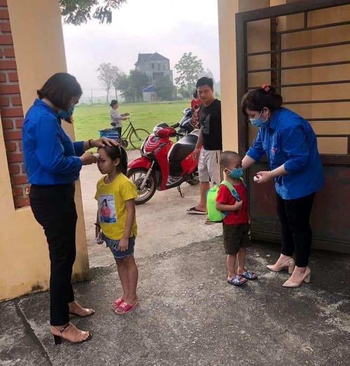 Đoàn viên, thanh niên huyện Chương Mỹ đón học sinh và đo thân nhiệt cho học sinh khi các em đến trường