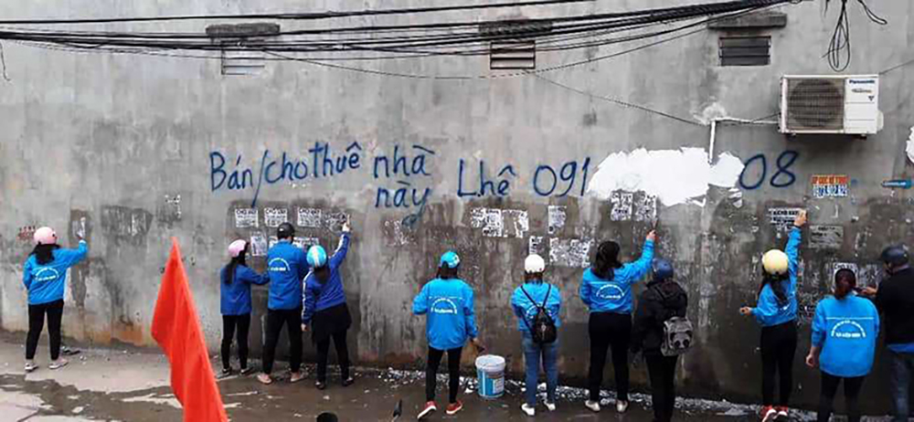 Đoàn viên, thanh niên huyện Thanh Trì xóa những tờ rơi quảng cáo gây mất mỹ quan đô thị. Ảnh: HD
