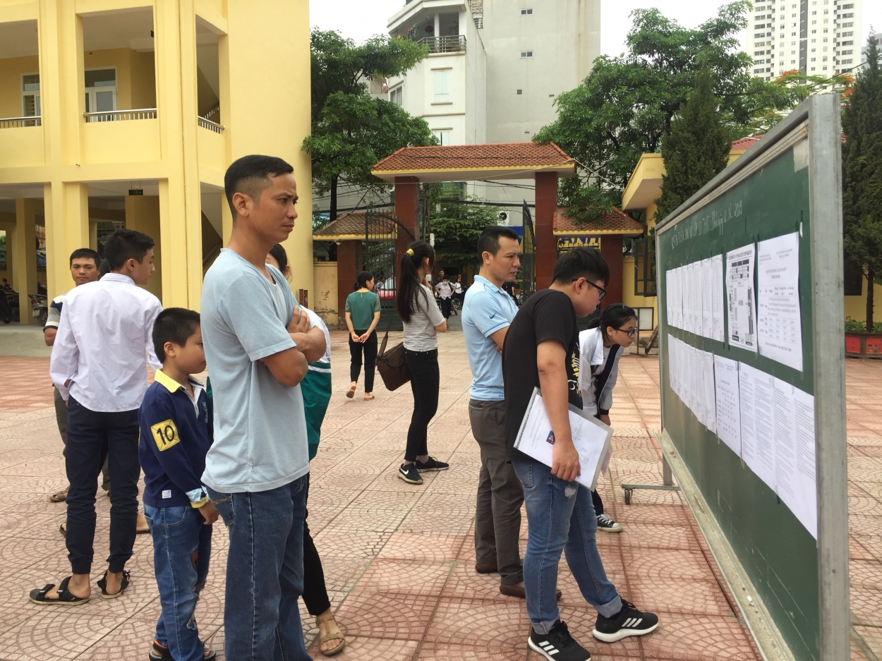 Các em thí sinh cùng phụ huynh xem số báo danh, phòng thi niêm yết tại bảng ở gần cổng trường
